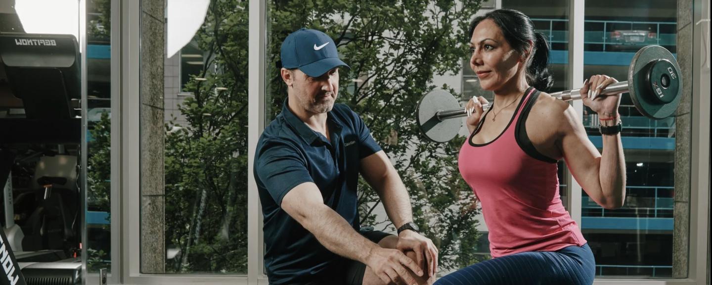 Trainer helping woman do squat lifts