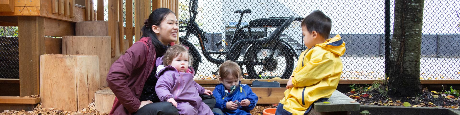 Early childhood educator with two children on playground