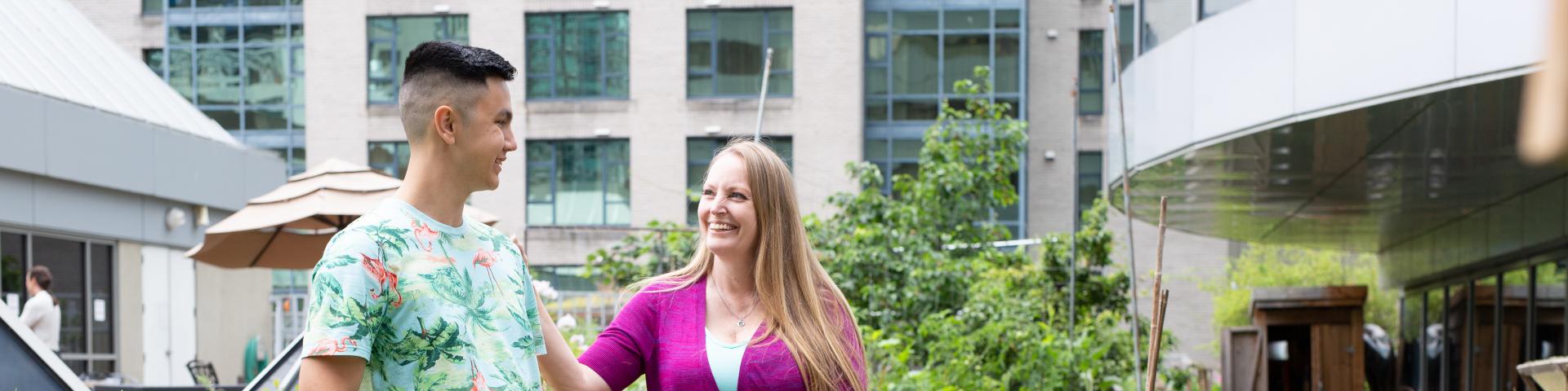 Young man in floral t-shirt and women in solid pink cardigan smiling at each other