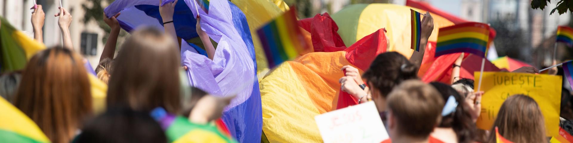 A crowd of people dressed in a rainbow of colours walk as part of a PRIDE parade