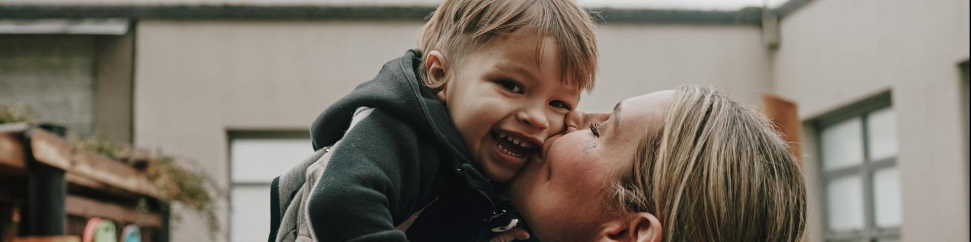 Mother kissing child 
