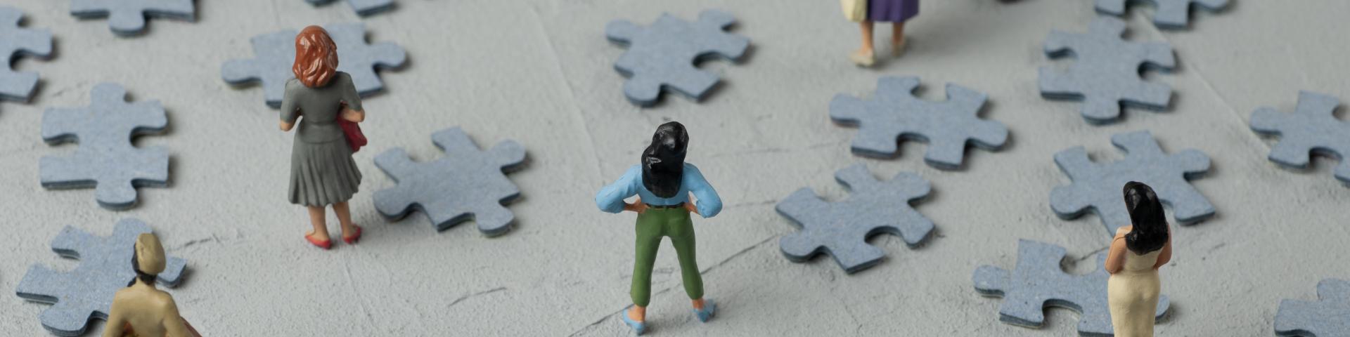 Woman figures looking at scattered puzzle pieces