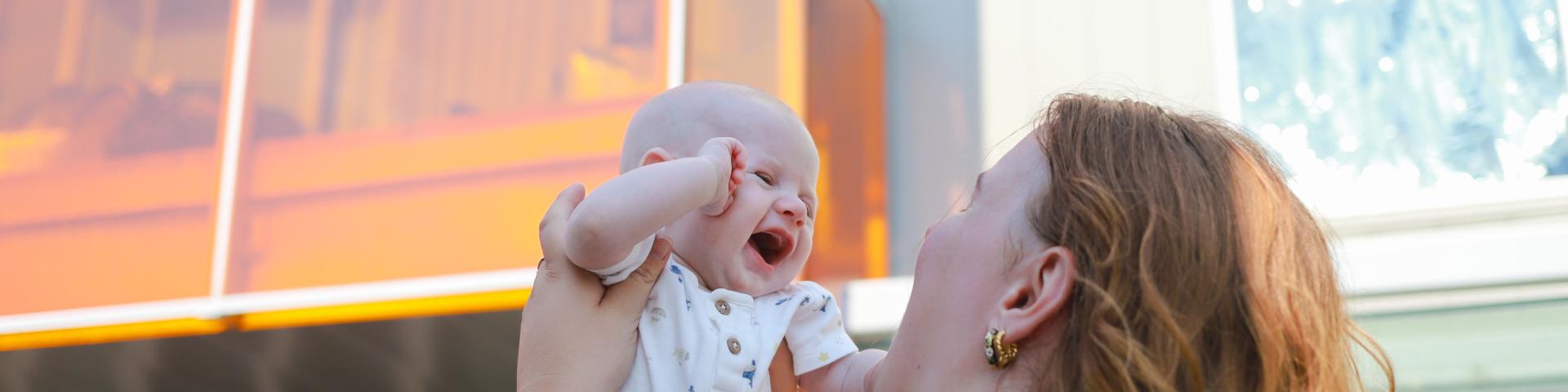 YWCA Housing participant holding her smiley baby up in the air