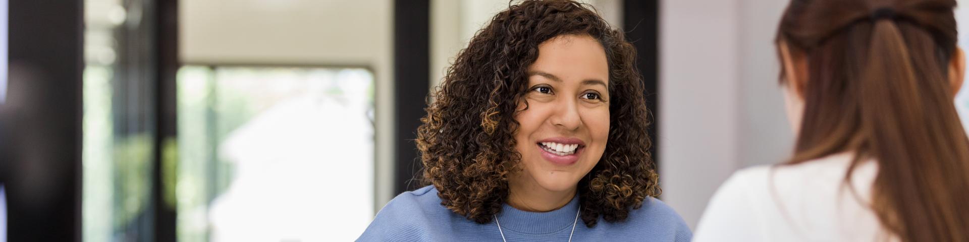The office manager holds onto a resume while speaking with the new intern they are considering.
