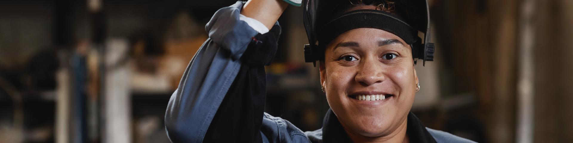 Closeup portrait of smiling female welder looking at camera in industrial factory