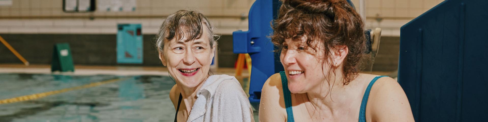 Two women smiling by pool