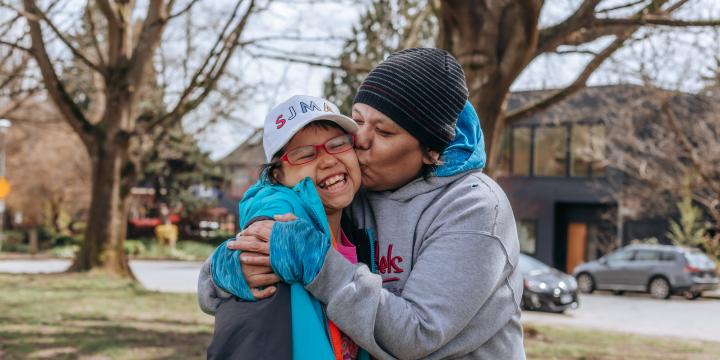 Mother kisses daughter on the cheek