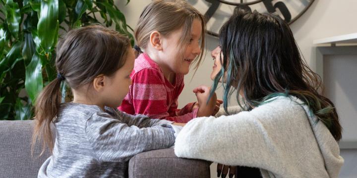 Mother and daughters looking at each other in the eyes, smiling