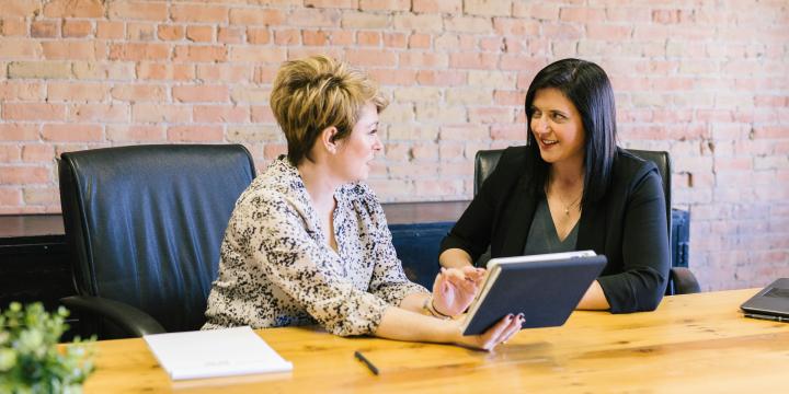 two women sitting on leather chairs in front of table