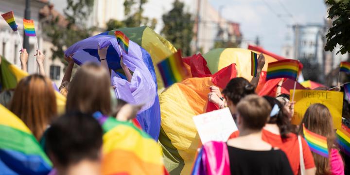 A crowd of people dressed in a rainbow of colours walk as part of a PRIDE parade