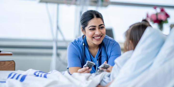 Female nurse in a hospital looking at a patient in bed