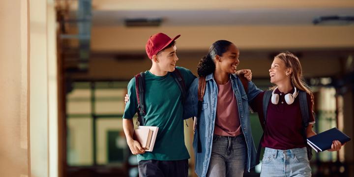 Group of teenagers laughing and talking as they walk down the hallway