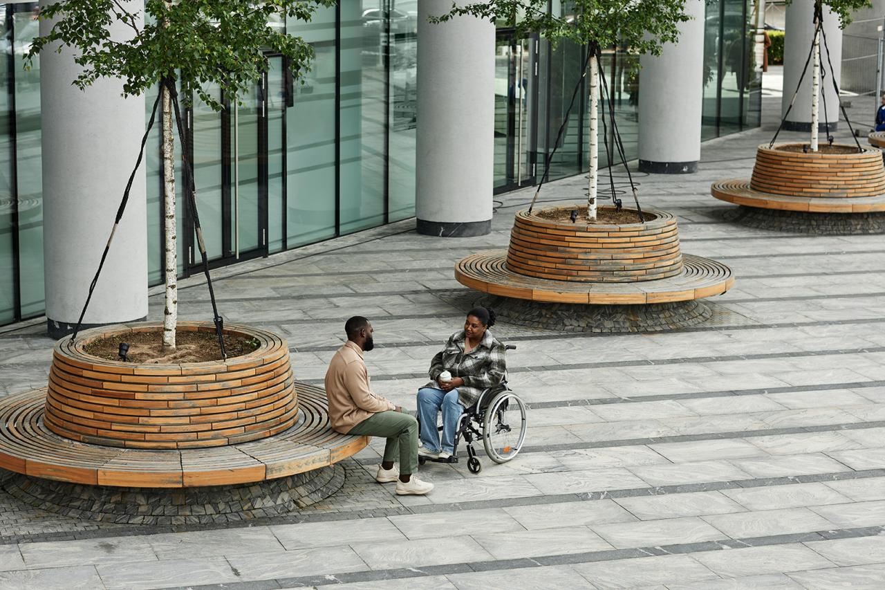 Two people who are Black-presenting, sitting across from each other, with one person in a wheelchair