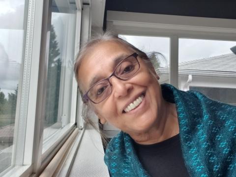 Photo of a smiling woman next to a window.