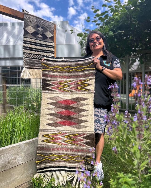 Vivian Mearns Notato - Musqueam weaving artist holding a wool weaving piece