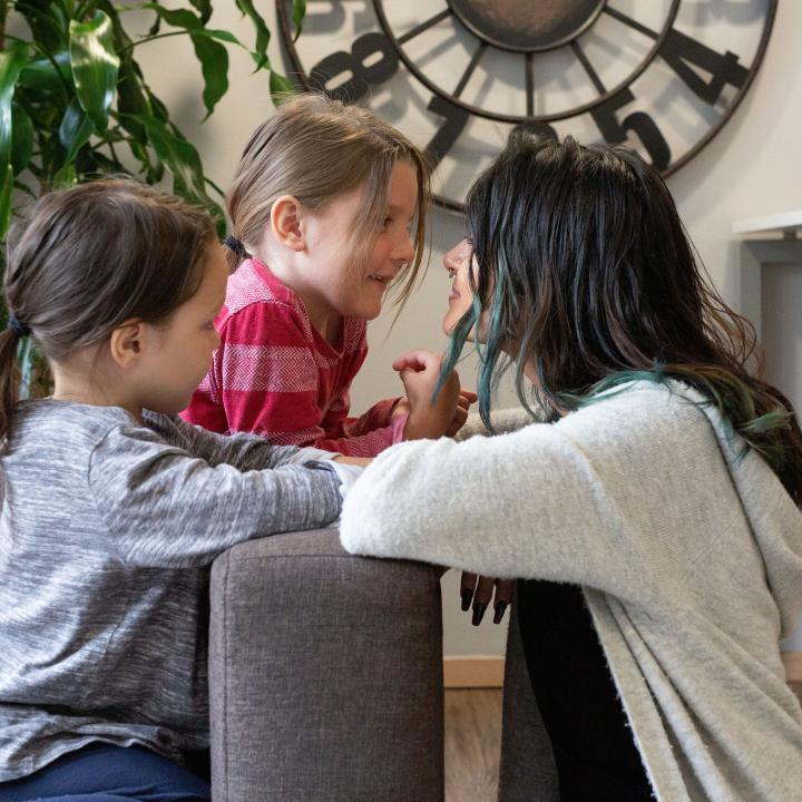Mother and two children looking at each other in a living quarters