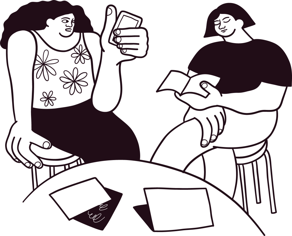 Two people gathering and reading around a table